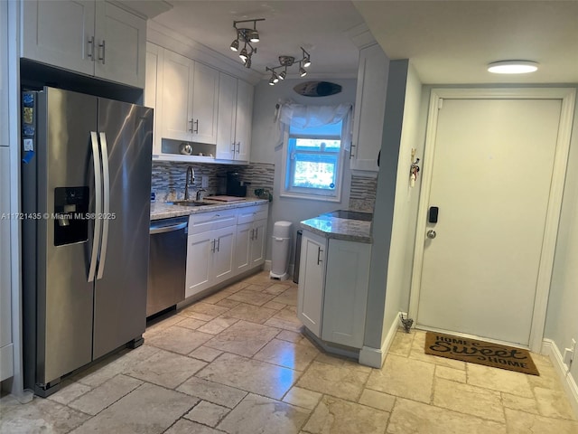 kitchen featuring white cabinetry, sink, light stone countertops, stainless steel appliances, and backsplash