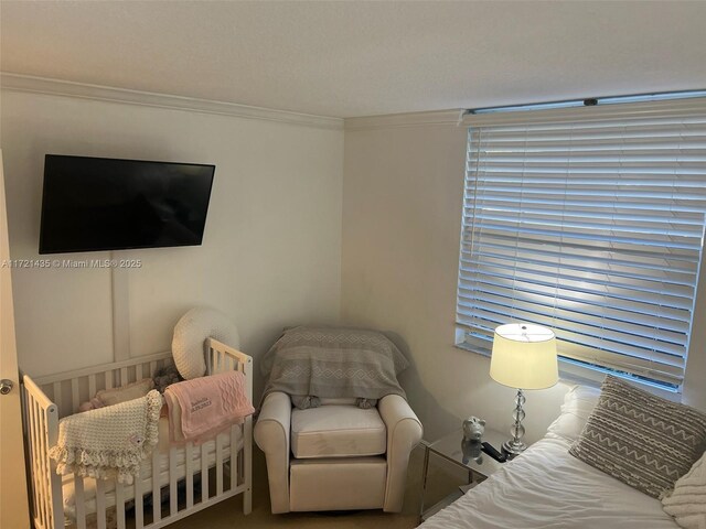 bedroom with a nursery area and ornamental molding