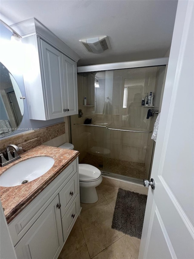 bathroom with toilet, vanity, tile patterned floors, and a shower with shower door