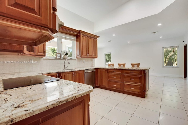 kitchen with black electric stovetop, sink, decorative backsplash, light stone counters, and kitchen peninsula