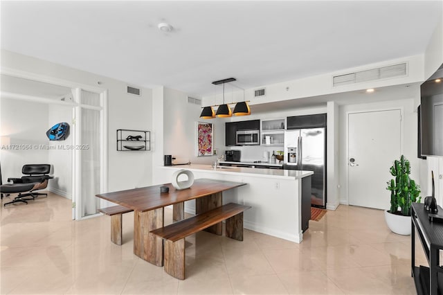 kitchen with decorative light fixtures, light tile patterned floors, appliances with stainless steel finishes, and kitchen peninsula