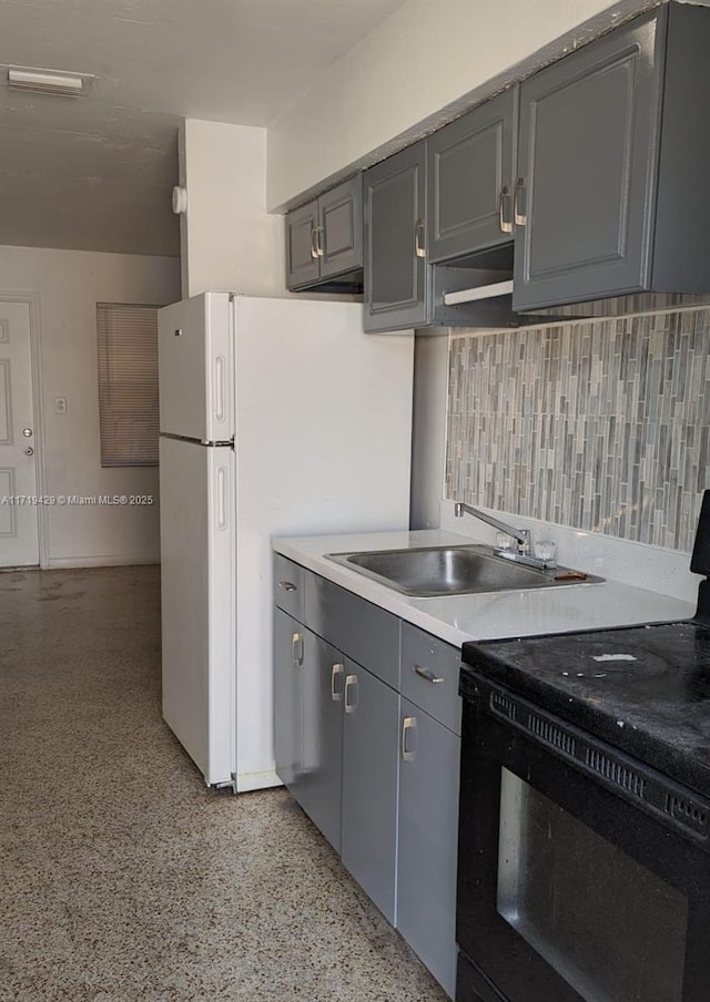 kitchen featuring gray cabinetry, white refrigerator, black range with electric stovetop, sink, and decorative backsplash