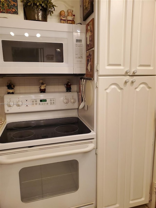 kitchen with white appliances, tasteful backsplash, and white cabinetry