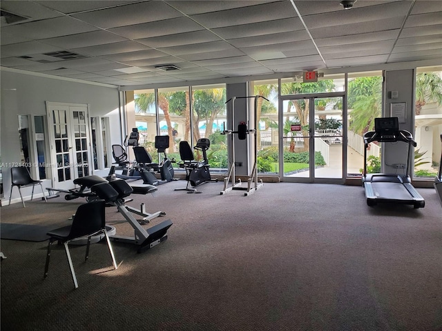 gym with carpet, a paneled ceiling, expansive windows, and french doors