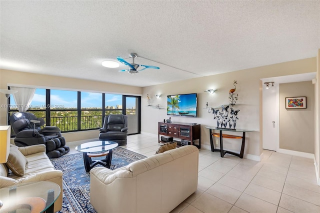 living room with ceiling fan, light tile patterned floors, and a textured ceiling