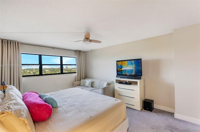 carpeted bedroom featuring ceiling fan and a textured ceiling