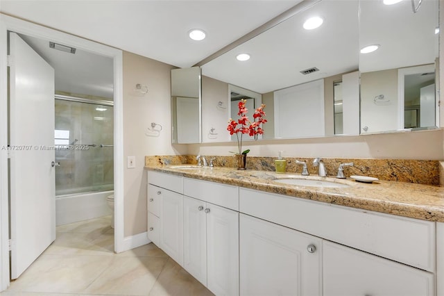 full bathroom with shower / bath combination with glass door, tile patterned flooring, vanity, and toilet