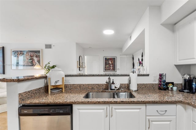 kitchen featuring sink, white cabinetry, stainless steel dishwasher, and dark stone counters