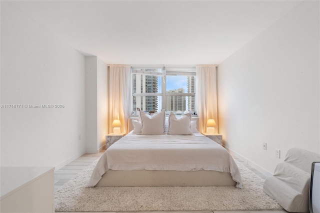 bedroom with a wall of windows and light hardwood / wood-style flooring