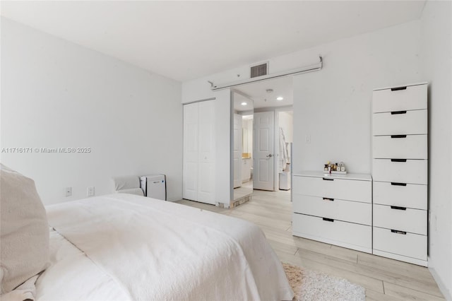 bedroom with light hardwood / wood-style floors and a closet