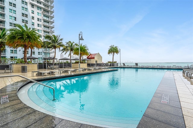 view of swimming pool featuring a water view and a patio