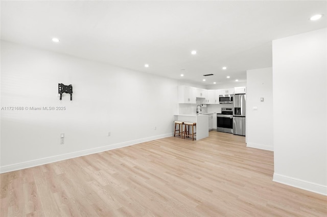 unfurnished living room featuring sink and light hardwood / wood-style floors