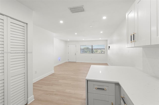 kitchen with gray cabinetry, white cabinets, and light wood-type flooring