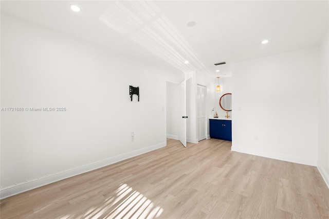 unfurnished bedroom featuring connected bathroom and light wood-type flooring