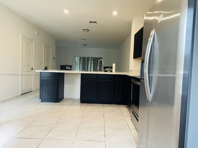 kitchen featuring visible vents, a peninsula, stainless steel appliances, light countertops, and a sink