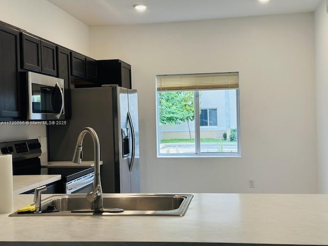 kitchen featuring appliances with stainless steel finishes, light countertops, dark cabinets, and recessed lighting