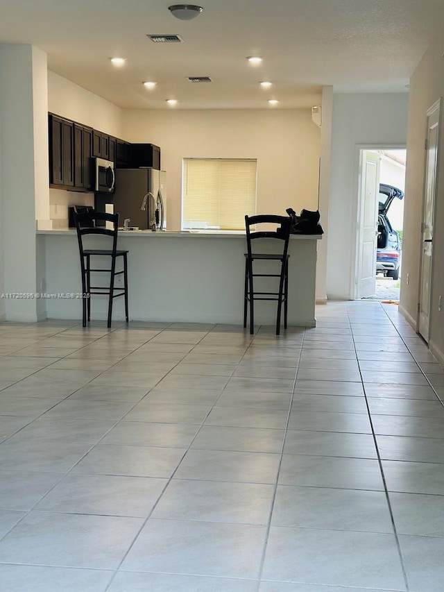 kitchen with stainless steel appliances, a breakfast bar, a peninsula, and visible vents