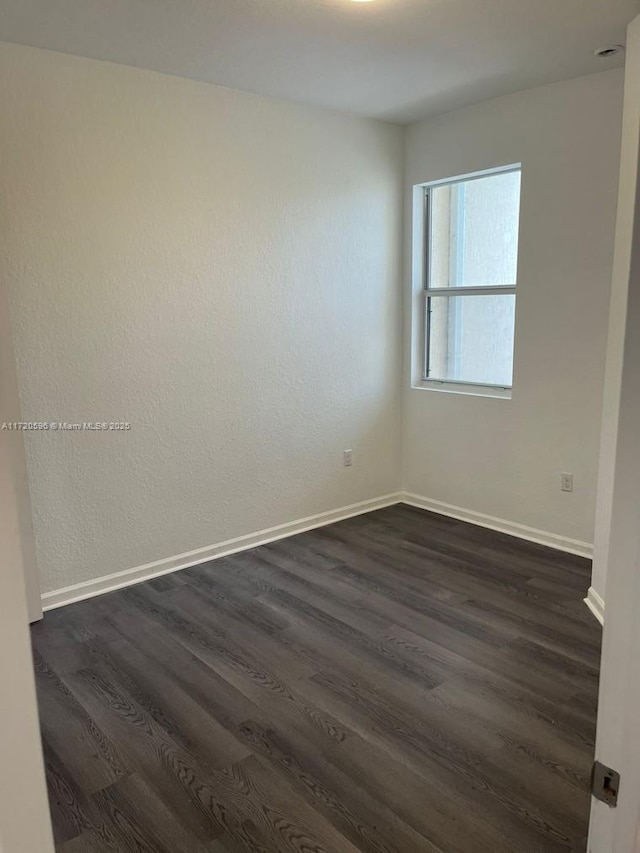 empty room featuring dark wood-style floors and baseboards