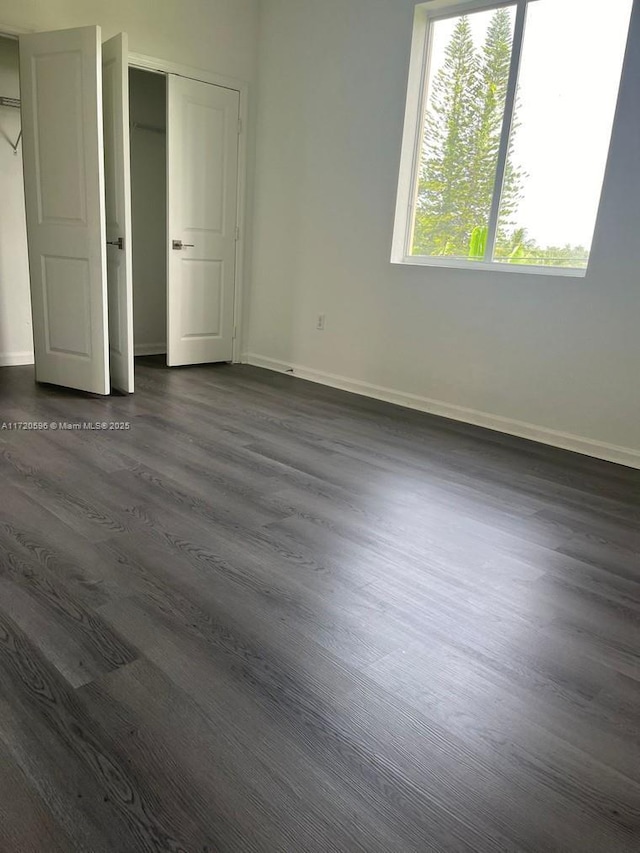 unfurnished bedroom with dark wood-style flooring and baseboards