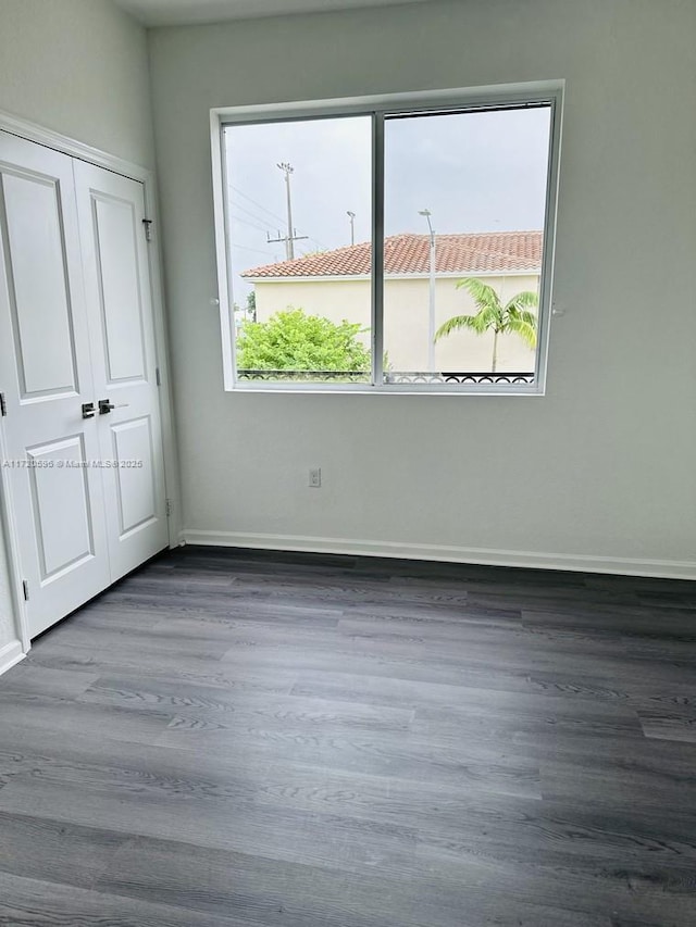 unfurnished room with a healthy amount of sunlight, baseboards, and wood finished floors