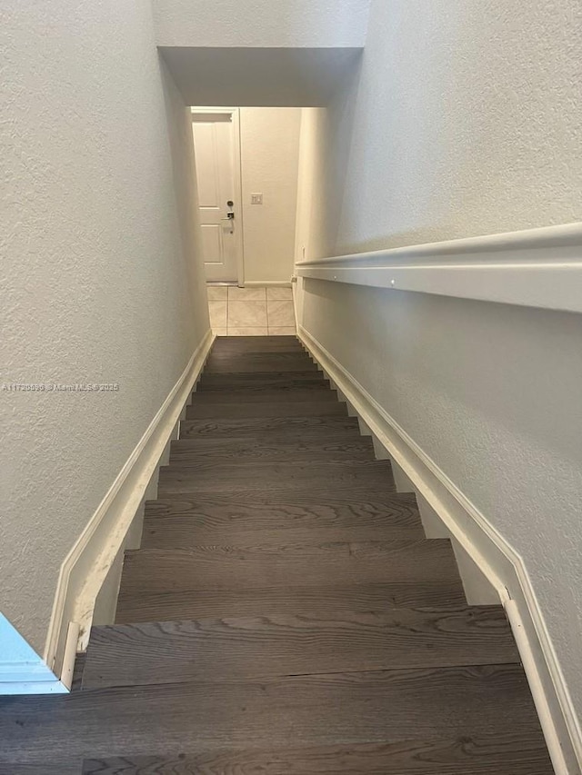 stairs featuring a textured wall and wood finished floors