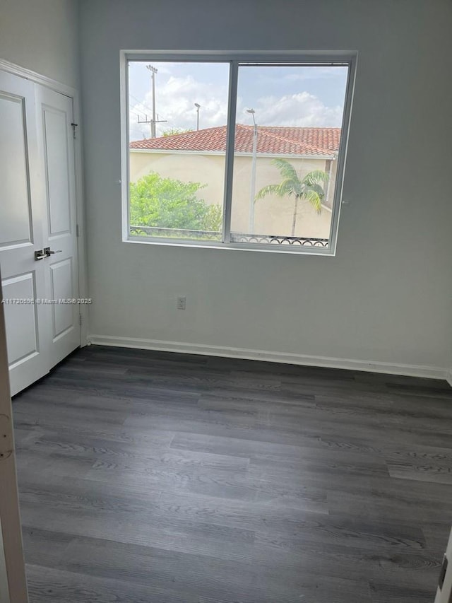 unfurnished bedroom with dark wood-style floors and baseboards