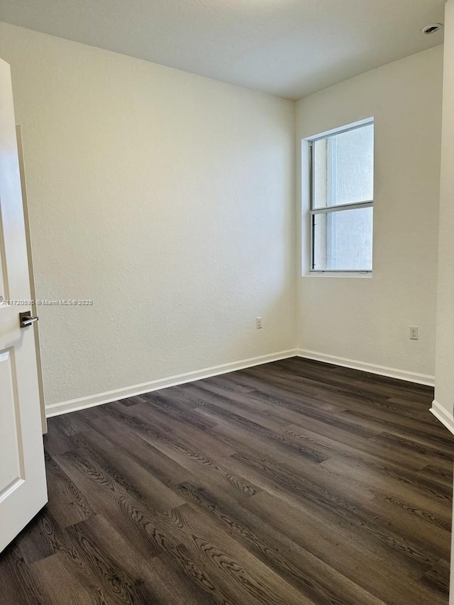 empty room with dark wood-style floors and baseboards