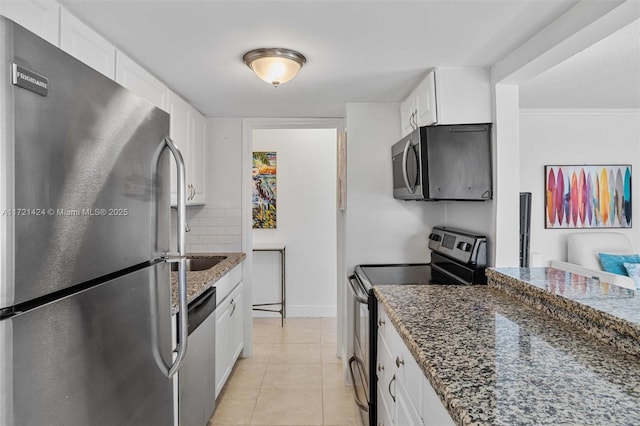 kitchen with tasteful backsplash, stainless steel appliances, light tile patterned floors, dark stone countertops, and white cabinets