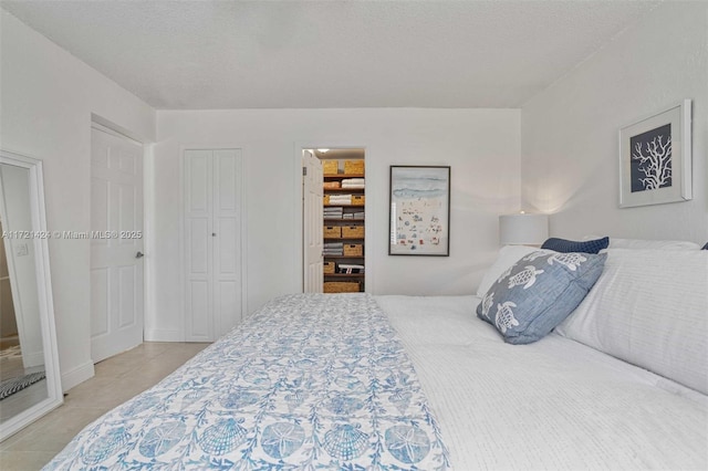 tiled bedroom with a closet and a textured ceiling