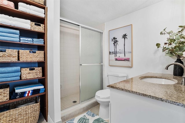 bathroom featuring a textured ceiling, vanity, a shower with door, tile patterned flooring, and toilet