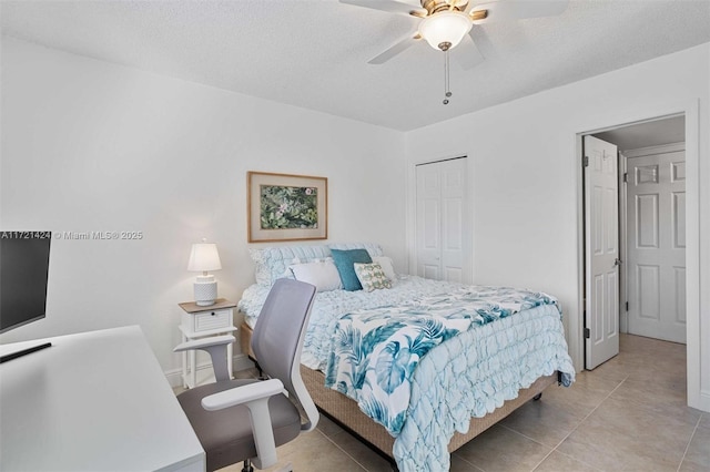 bedroom featuring ceiling fan, a closet, light tile patterned flooring, and a textured ceiling