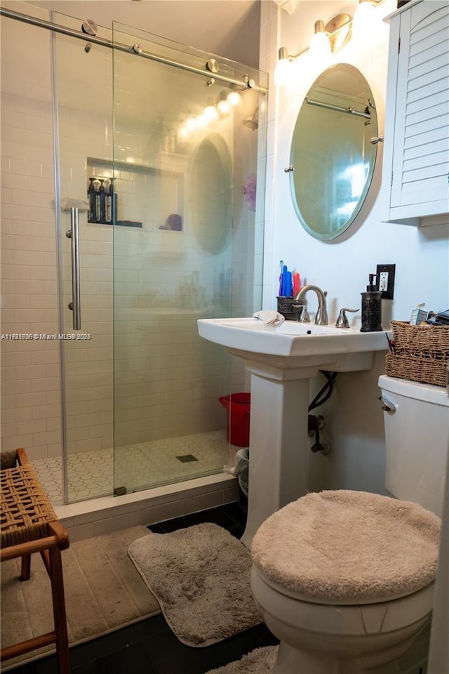 bathroom with tile patterned flooring, toilet, and a shower with shower door