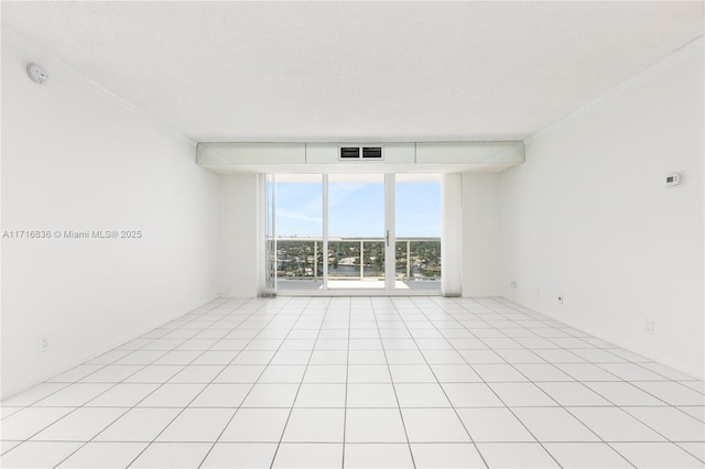 empty room featuring ornamental molding, light tile patterned floors, a textured ceiling, and a wall of windows