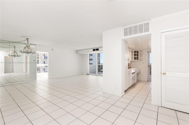 empty room with an inviting chandelier, light tile patterned floors, and ornamental molding