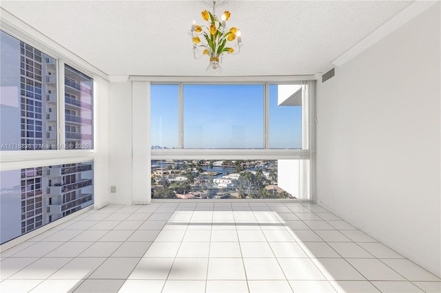 spare room featuring expansive windows, ornamental molding, a textured ceiling, and light tile patterned floors