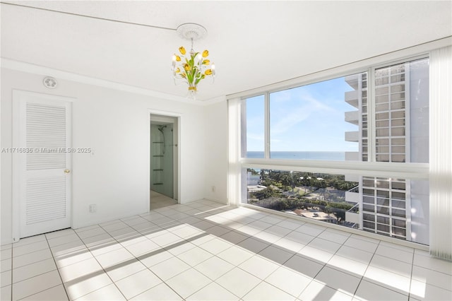 empty room featuring ornamental molding, light tile patterned flooring, and a water view