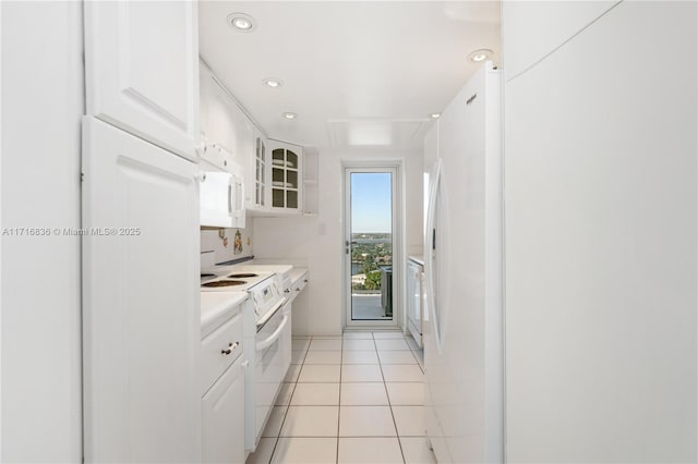 kitchen featuring light tile patterned floors, white appliances, and white cabinets