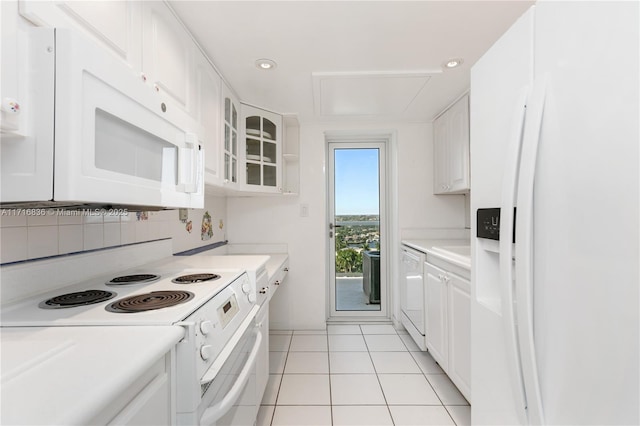 kitchen with tasteful backsplash, white appliances, light tile patterned floors, and white cabinets