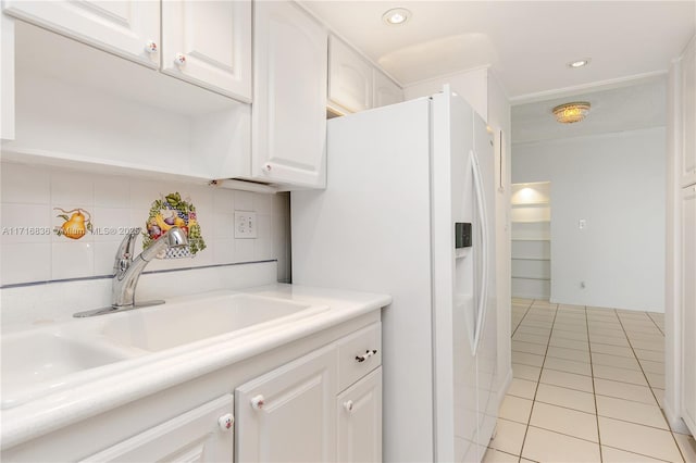 kitchen with tasteful backsplash, sink, white cabinets, white refrigerator with ice dispenser, and light tile patterned floors