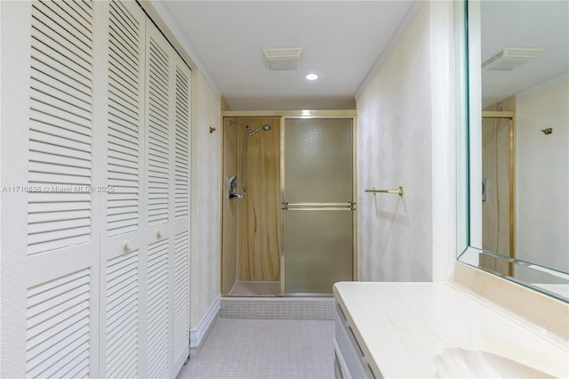 bathroom with an enclosed shower, vanity, and tile patterned flooring