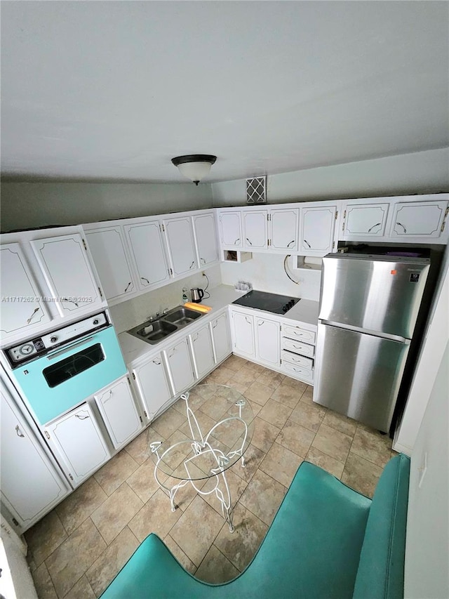 kitchen with white cabinets, oven, sink, stainless steel fridge, and black electric cooktop