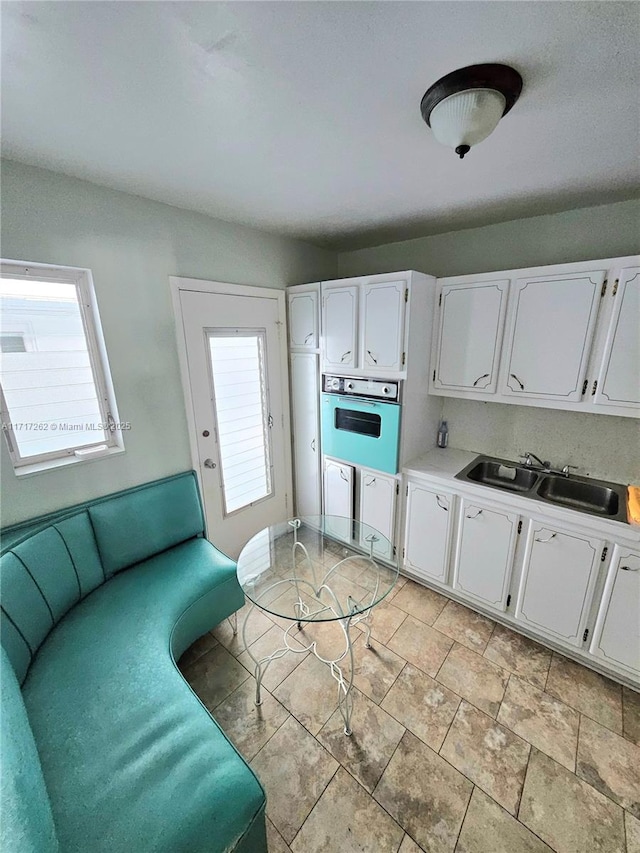 kitchen with white oven, plenty of natural light, and white cabinets