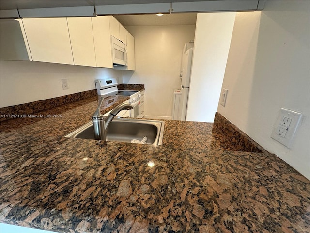 kitchen with dark stone countertops, sink, white cabinets, and white appliances