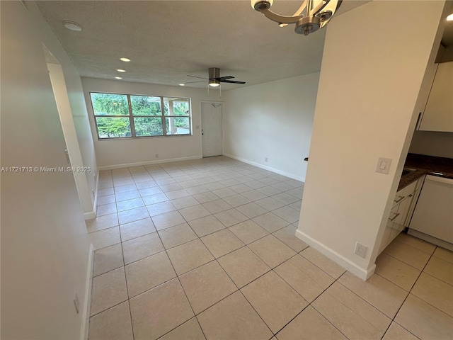 tiled spare room with ceiling fan with notable chandelier