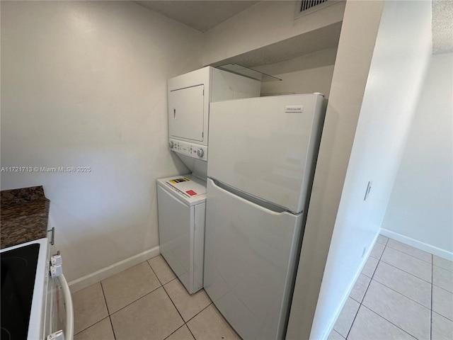 washroom with light tile patterned flooring and stacked washing maching and dryer