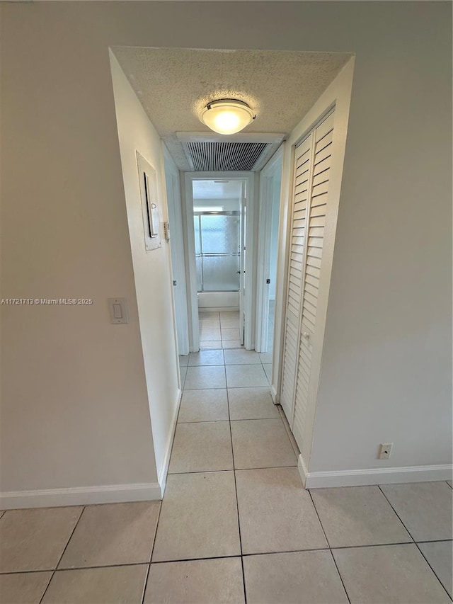 hall with light tile patterned floors and a textured ceiling