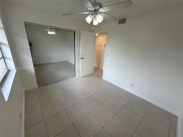 empty room with ceiling fan and light tile patterned floors