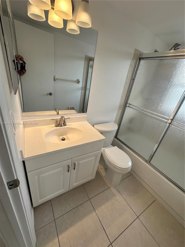 full bathroom featuring tile patterned flooring, vanity, toilet, and shower / bath combination with glass door