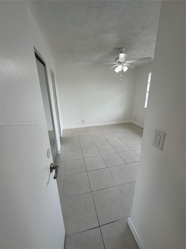 unfurnished room with ceiling fan, light tile patterned floors, and a textured ceiling