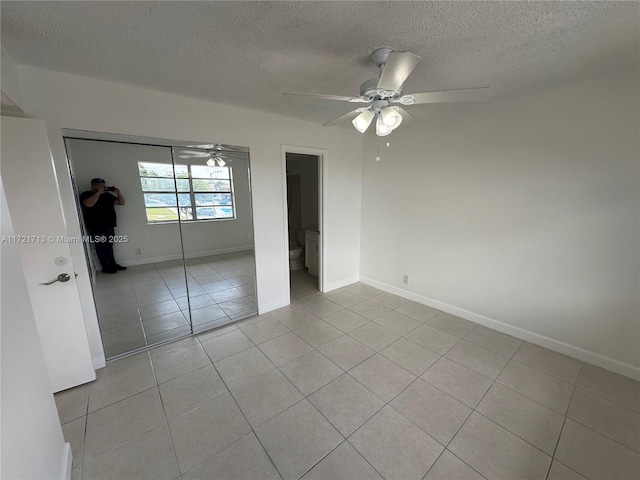 unfurnished bedroom featuring light tile patterned floors, a textured ceiling, and ceiling fan